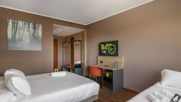 Una habitación de hotel con dos camas, un escritorio y un espejo.