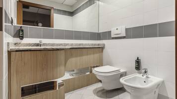 A modern bathroom with a wooden vanity, a bidet, and a sink.