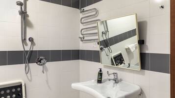Une salle de bain équipée d’une douche, d’un lavabo, d’un miroir et d’un distributeur de gel hydroalcoolique.