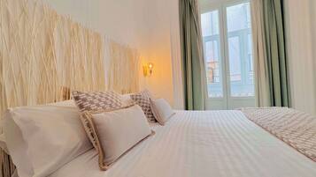 A hotel room with a bed, a wall-mounted light, and a window with curtains.