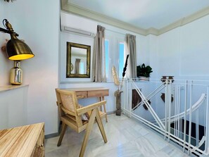 A modern room with a wooden desk, a lamp, a mirror, and a white railing. - Hotel Boutique Las Cortes de Cádiz (Cádiz)
