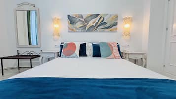 Een hotelkamer met een groot bed, twee nachtkastjes, een klein bureau, een spiegel en wandlampen.