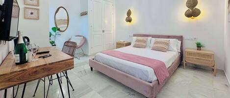 A modern bedroom with a large bed, a desk, a chair, and a wardrobe.
