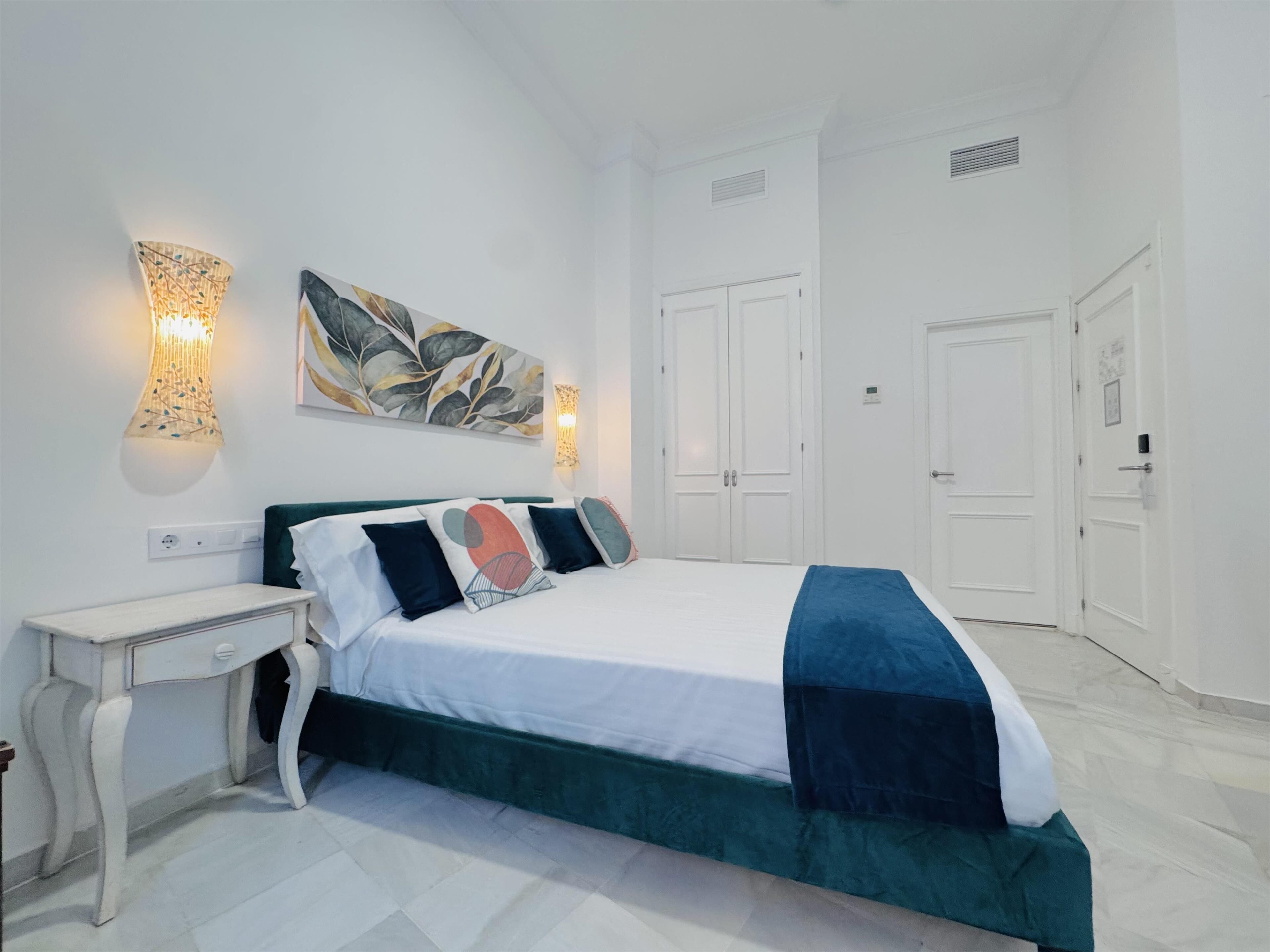 A bedroom with a bed, bedside tables, wall art, and a wardrobe.