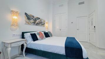 A bedroom with a bed, bedside tables, wall art, and a wardrobe.