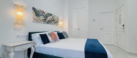 Un dormitorio con cama, mesitas de noche, decoración en la pared y armario.