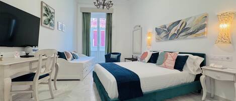 Habitación de hotel con cama, escritorio, silla, televisor y candelabro.