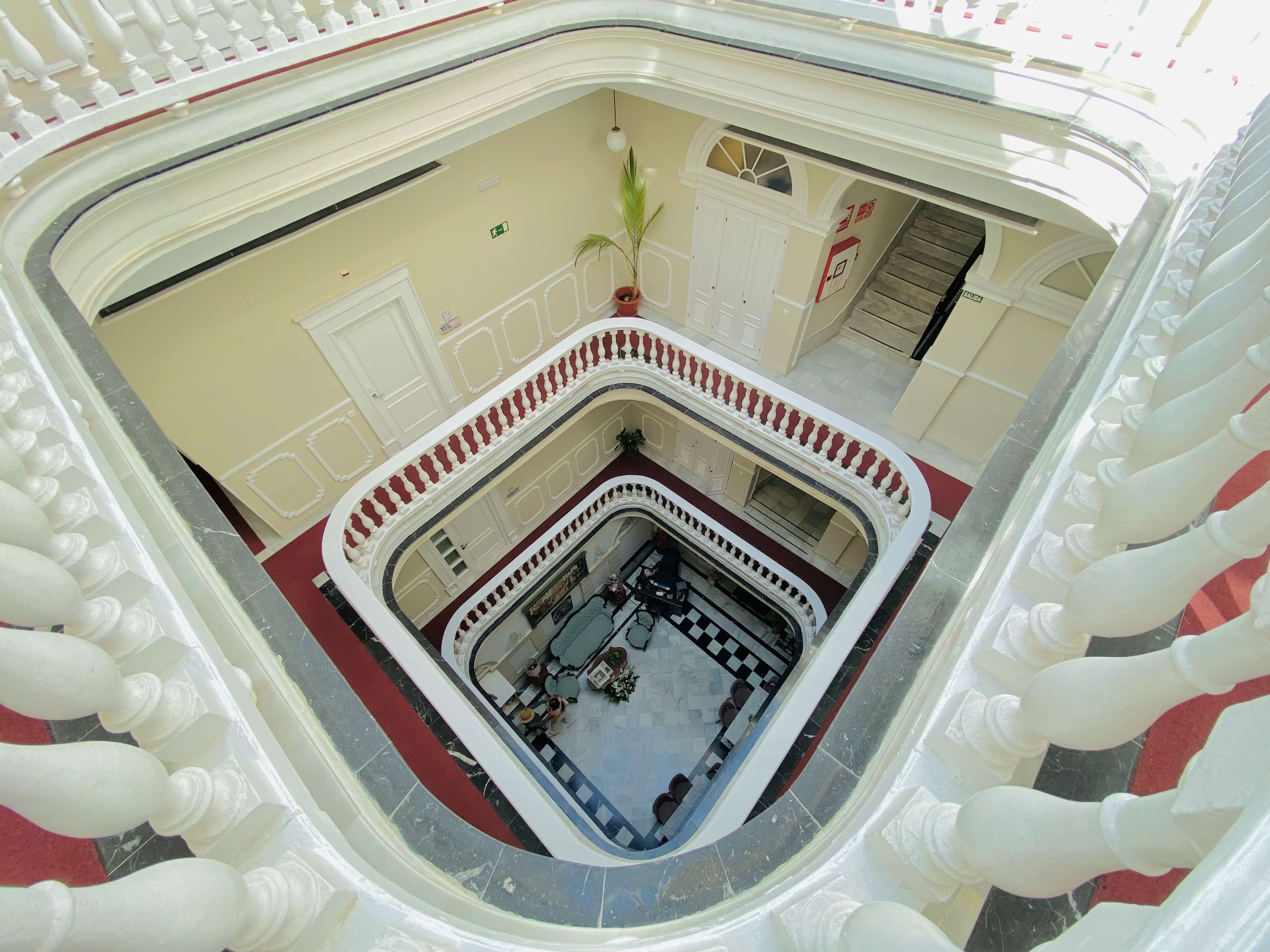 Un atrium à plusieurs niveaux, doté d’une cour intérieure, de balustrades blanches et d’un sol recouvert d’une moquette rouge.