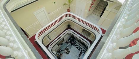 A multi-level atrium with a central courtyard, white balustrades, and a red carpeted floor.