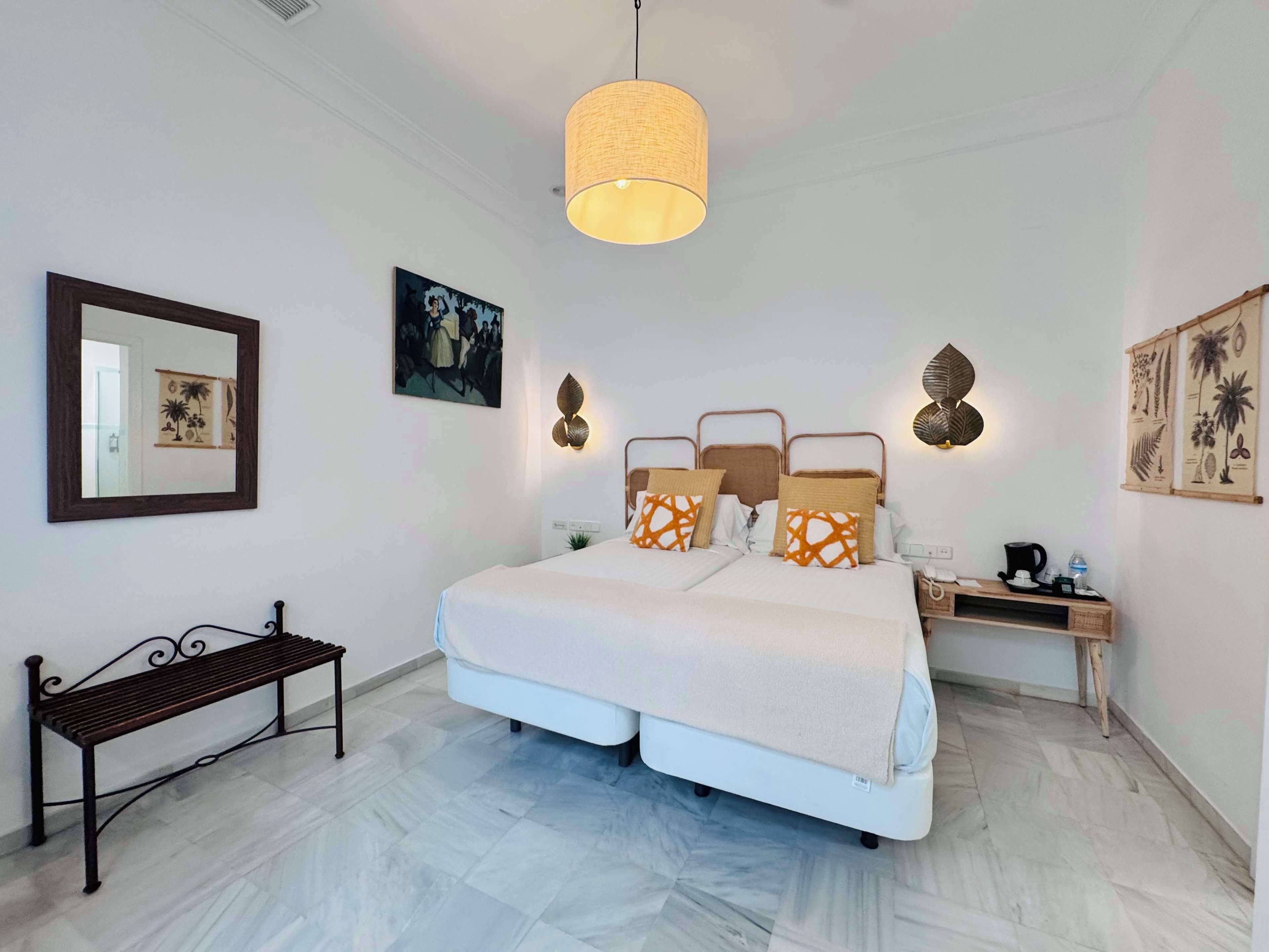 Ein Schlafzimmer mit einem Bett, Nachttischen, einer Bank und Wanddekoration.