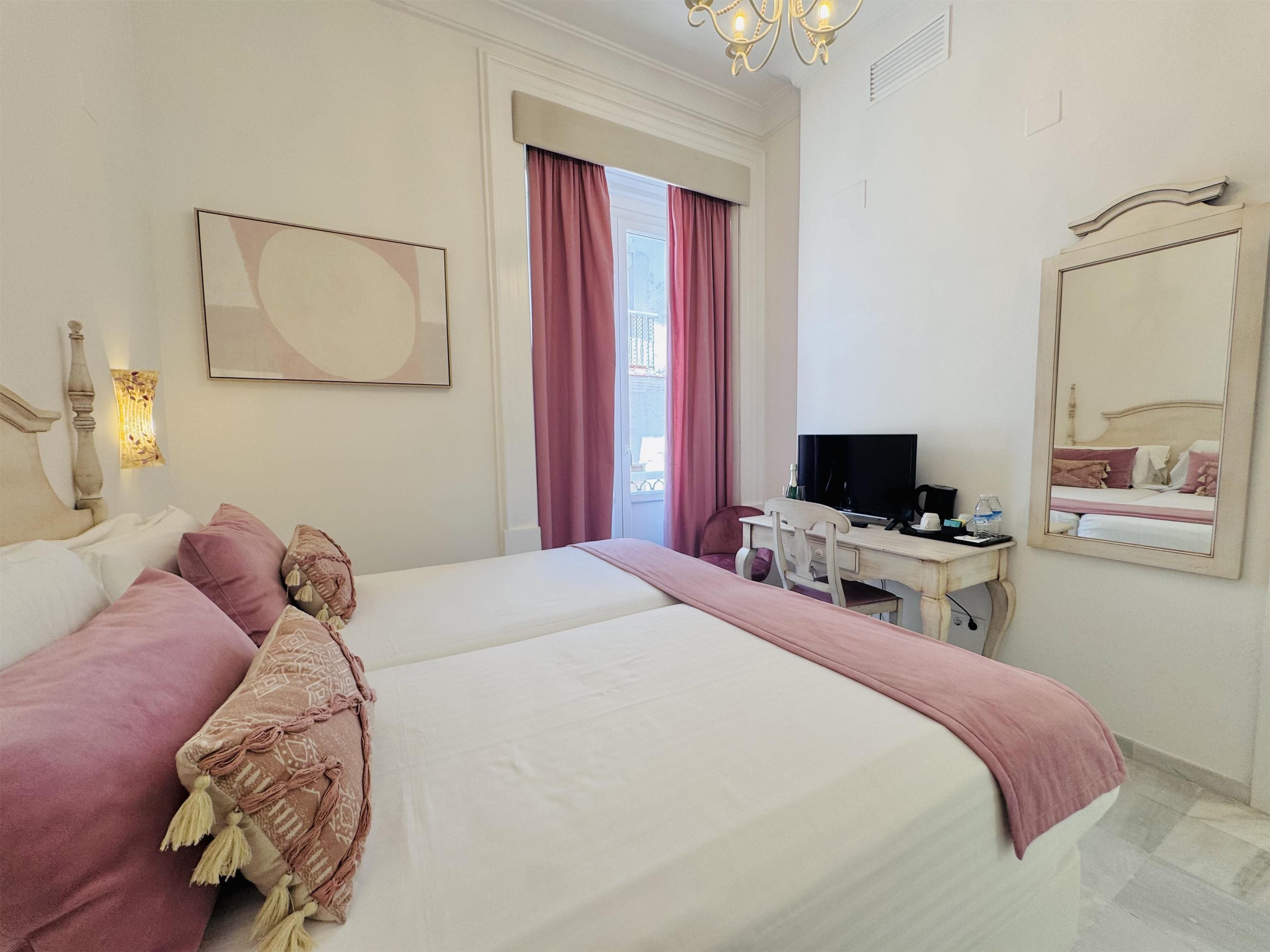 Habitación de hotel con una cama grande, un escritorio con computadora, un televisor y un espejo.