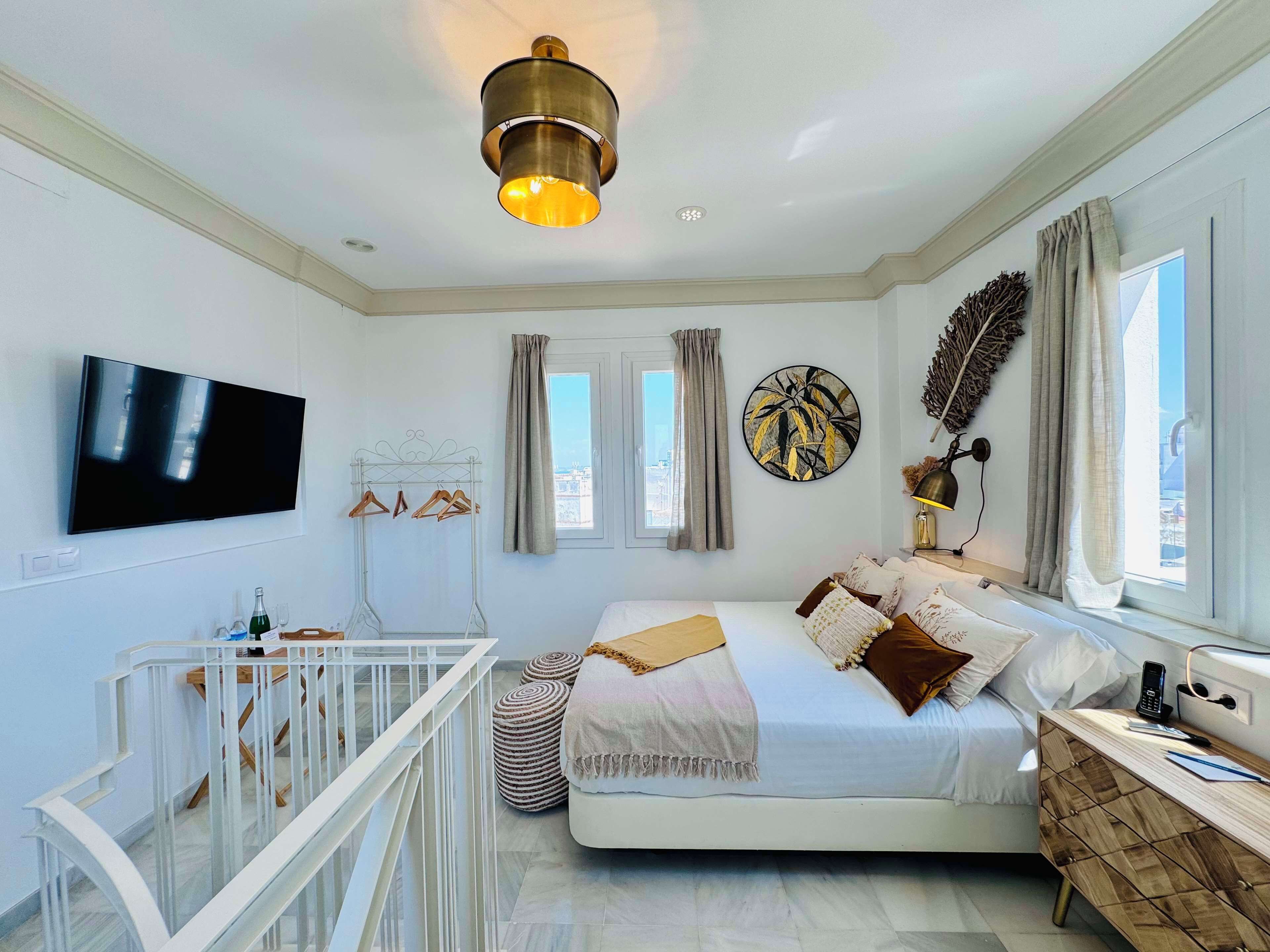 Un dormitorio moderno con cama, televisor, cuna y ventana con cortinas.