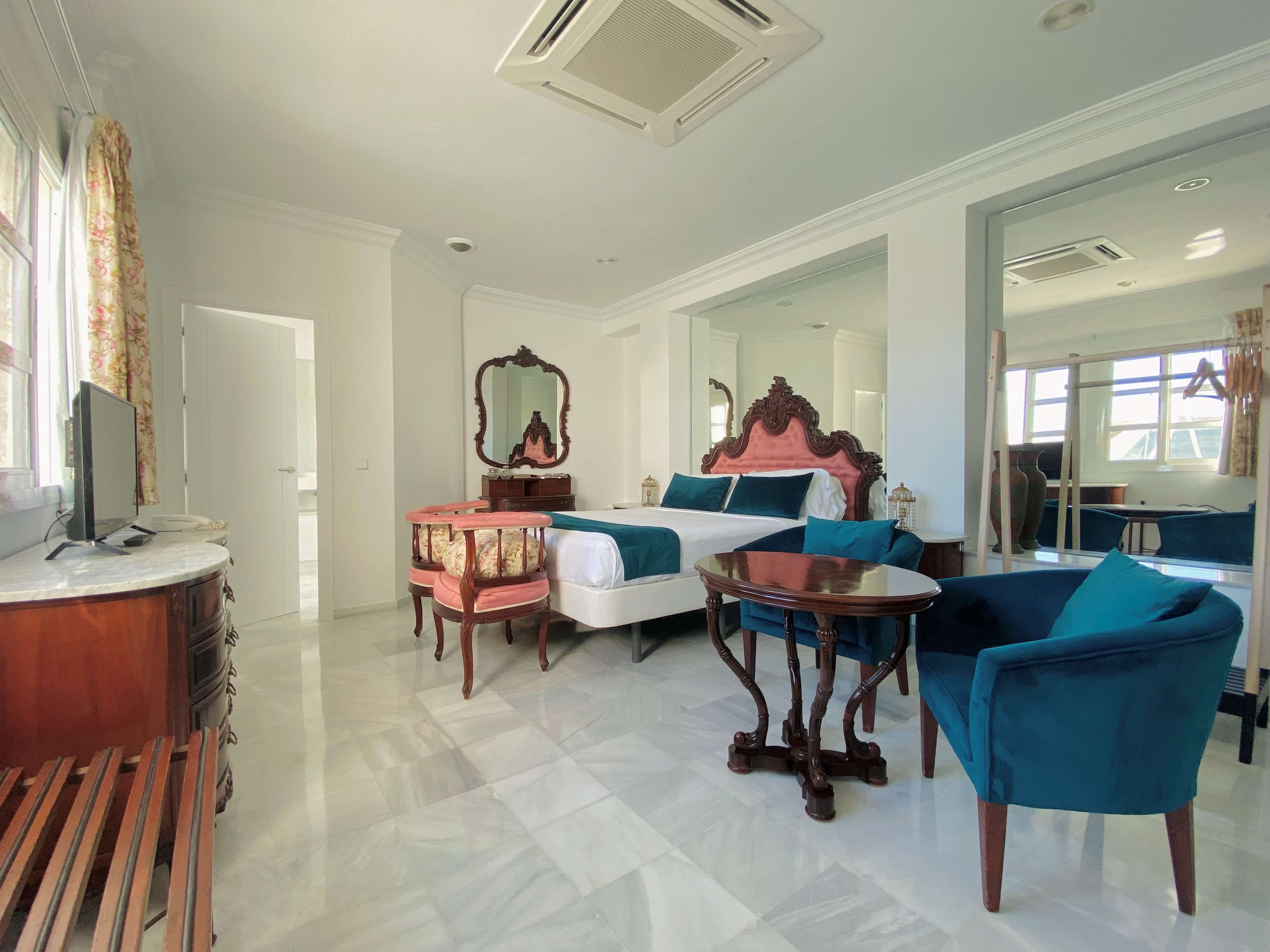 Habitación de hotel con una cama grande, un escritorio, una silla y un espejo.