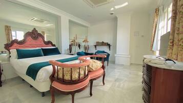 A hotel room with a large bed, a vanity with a mirror, a chair, and a desk.