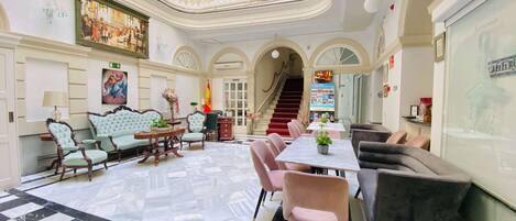Une salle à manger spacieuse avec un sol à carreaux, un mobilier élégant et un balcon doté d’une balustrade.