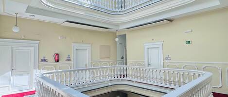 Un atrium à plusieurs niveaux, doté d’un espace central ouvert, de balustrades blanches et d’une moquette rouge.