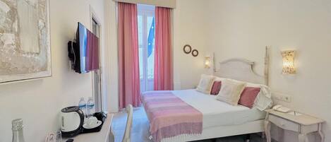 A hotel room with a bed, bedside table, TV, and a bottle of champagne.