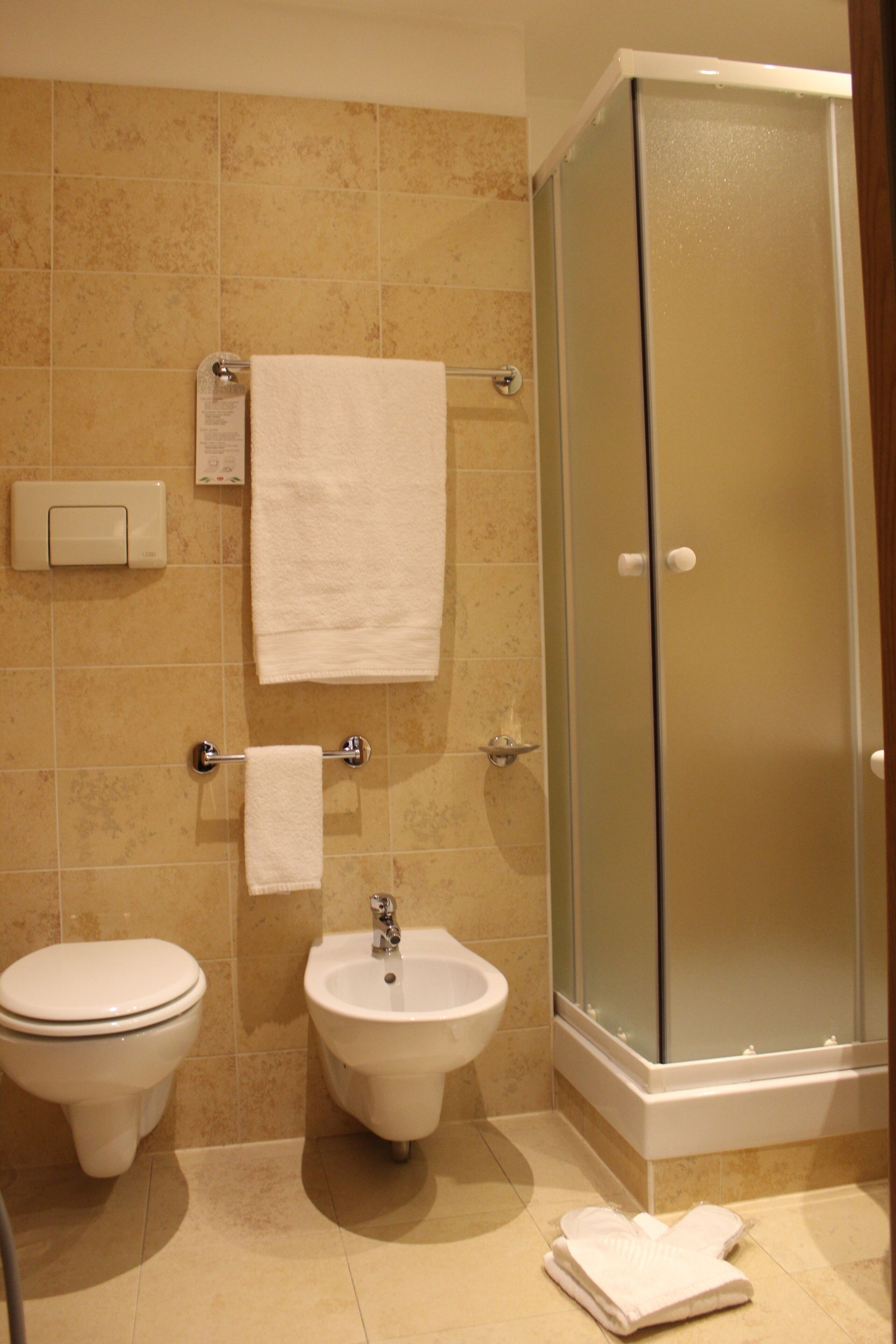 Un baño con inodoro, bidé y ducha con mampara de vidrio.