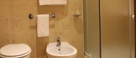 A bathroom with a toilet, bidet, and a glass-enclosed shower.