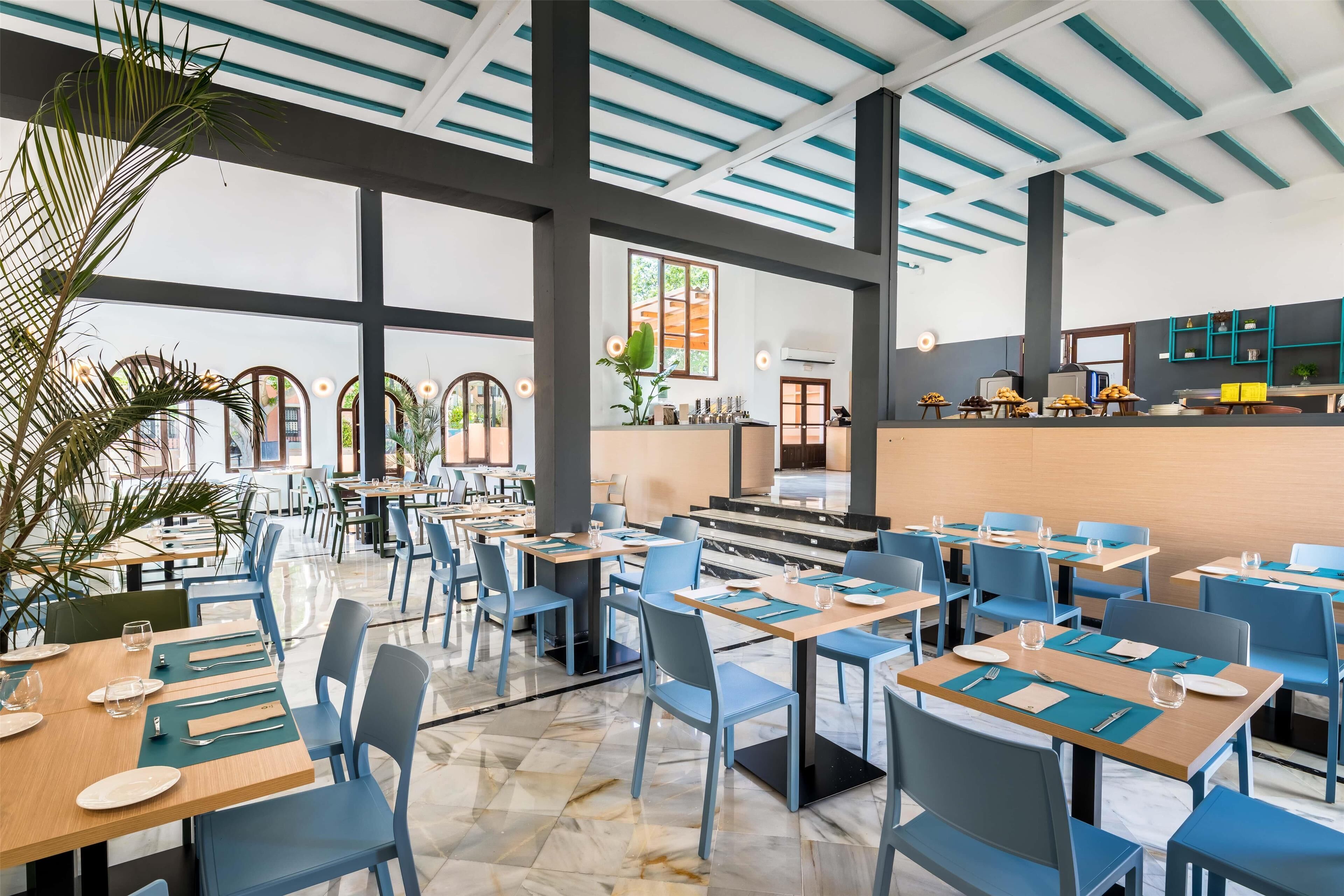 Un restaurante espacioso con techos altos, ventanas amplias y una decoración interior moderna.