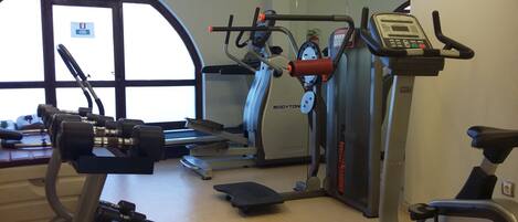 A gym with cardio machines, dumbbells, and a treadmill.