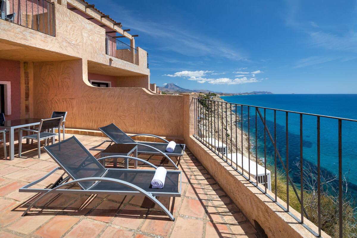 Une terrasse avec des chaises longues et vue sur la mer.