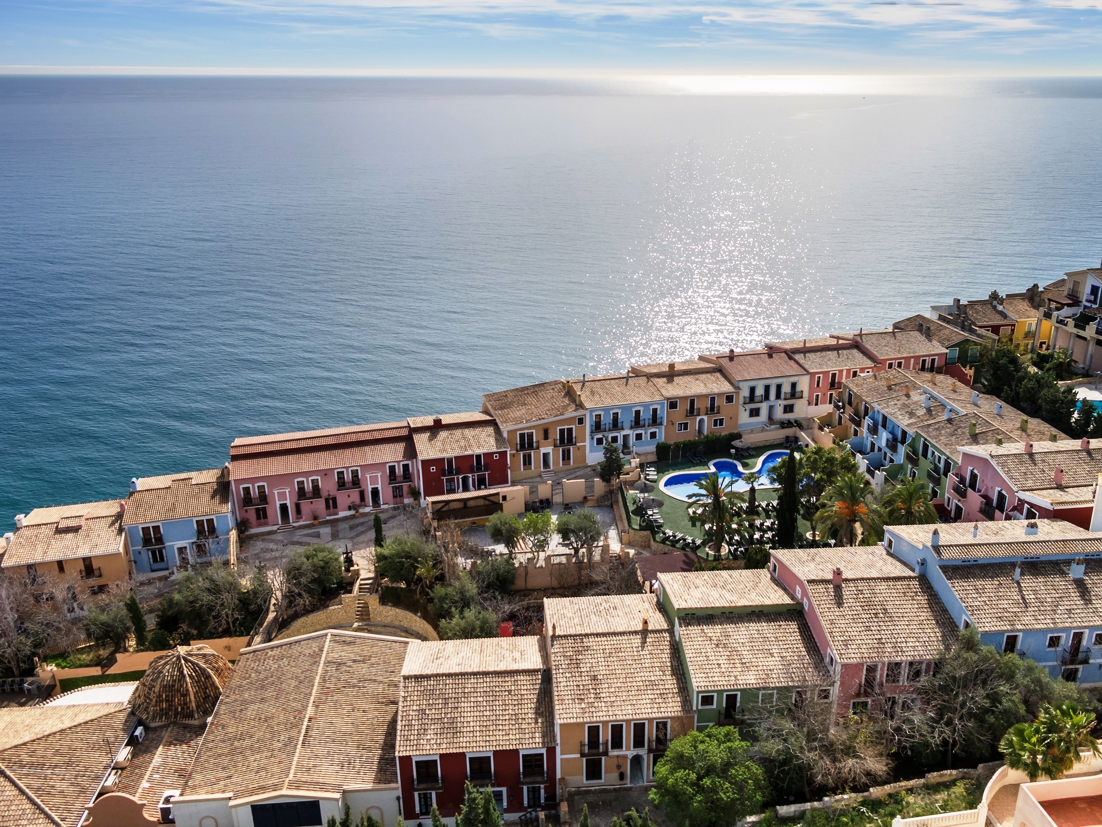 A coastal town with colorful buildings, a swimming pool, and a view of the sea.