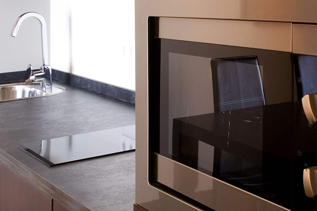 Une cuisine moderne avec un évier en acier inoxydable et une cuisinière noire.