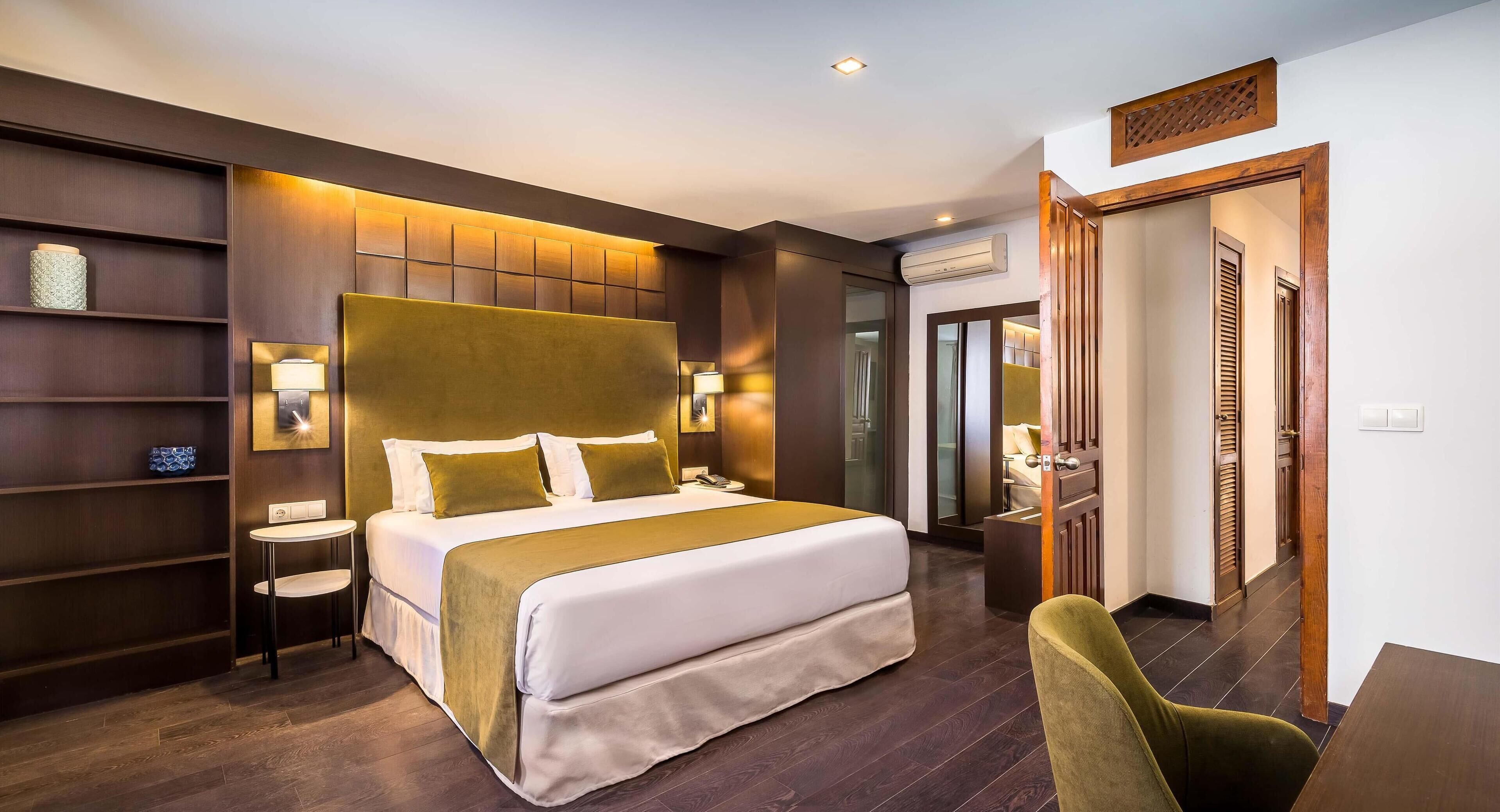 Una camera d'albergo moderna con un letto grande, un comodino, una sedia, una scrivania e un armadio.