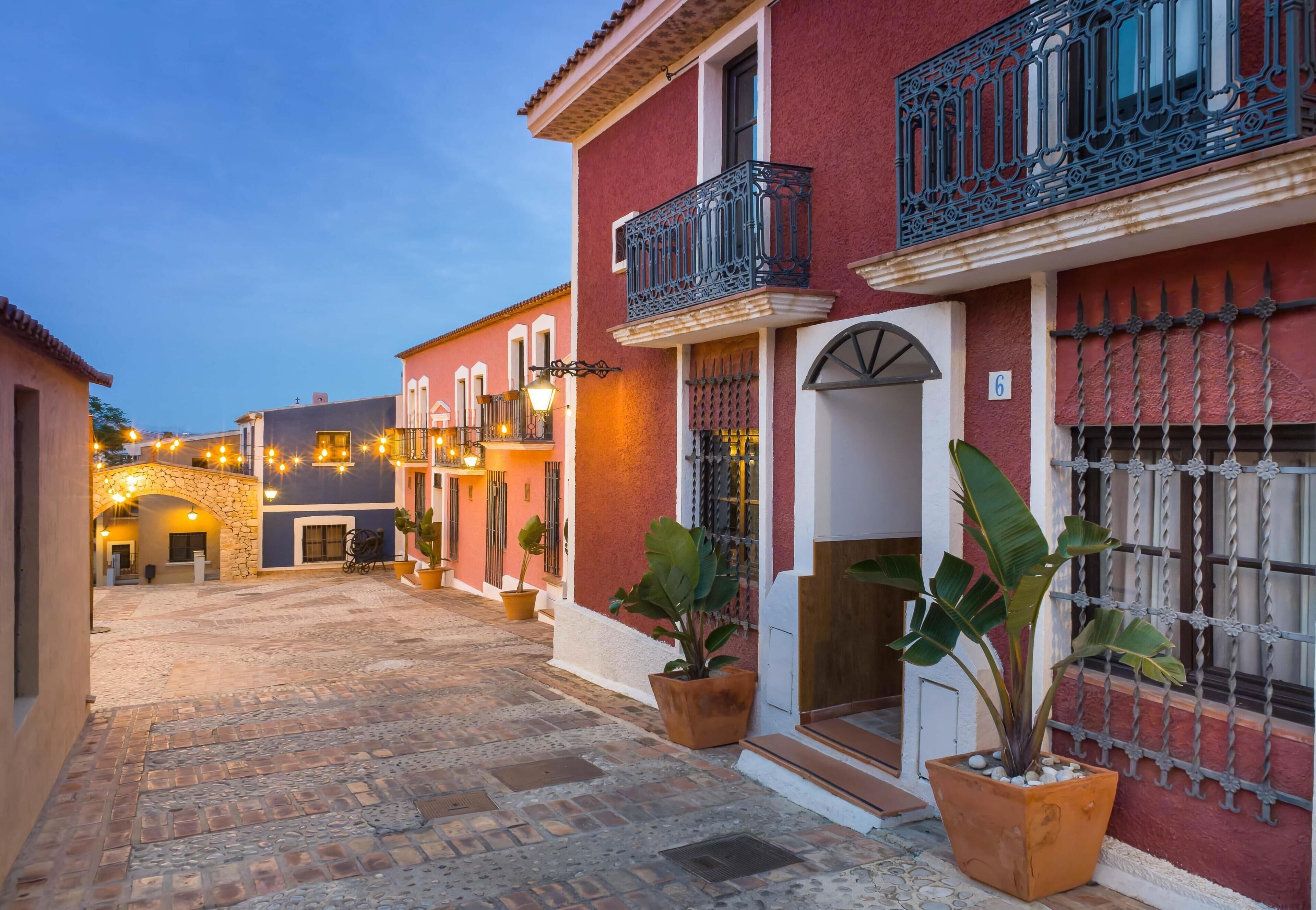 Una calle adoquinada con edificios que tienen balcones y portones de hierro forjado.