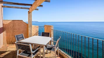Eine Terrasse mit Tisch und Stühlen mit Blick auf das klare, blaue Meer.