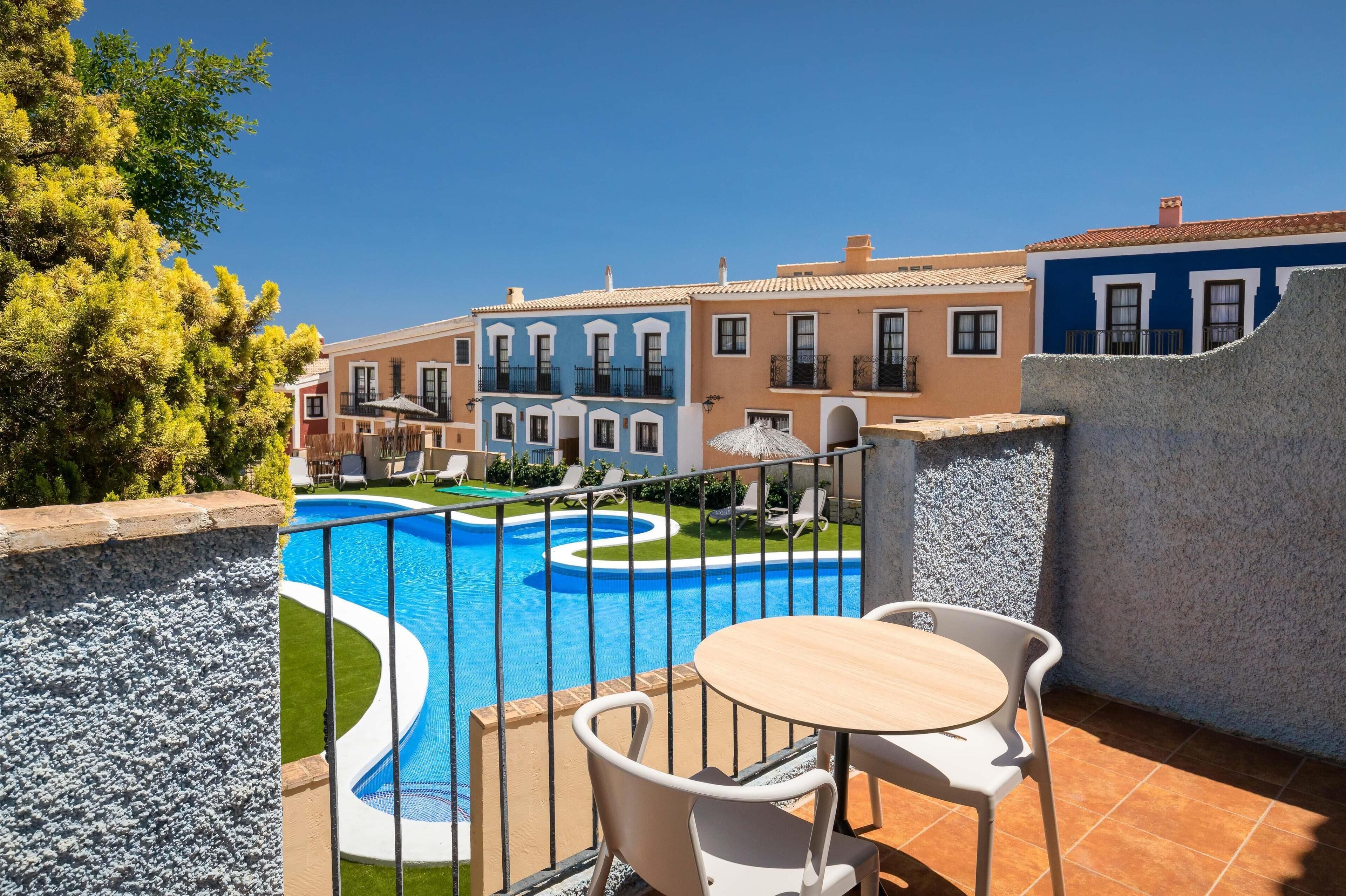 Zona de piscina con diseño circular, rodeada por una valla y adyacente a un edificio con balcones.