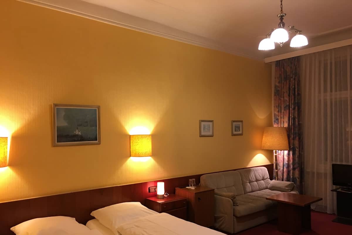 Ein Hotelzimmer mit zwei Betten, einem Schlafsofa, einem Fernseher und einer Lampe.