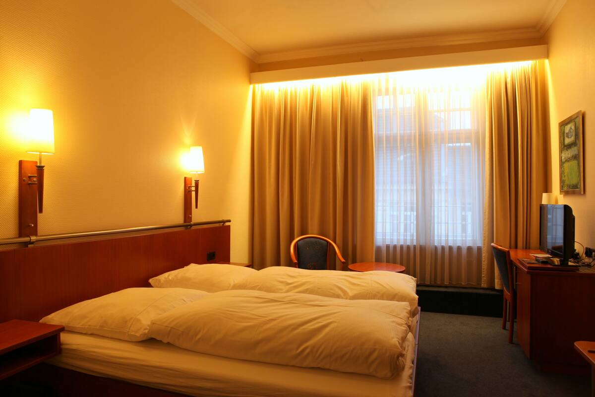 Ein Hotelzimmer mit einem Bett, einem Schreibtisch, einem Sessel und einem Fernseher.