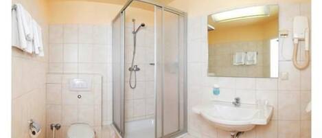 Une salle de bain avec une douche à parois de verre, un lavabo et des toilettes.