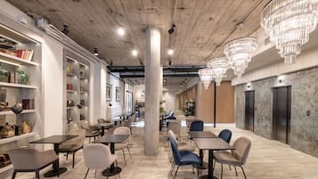 Ein modernes Interieur mit Tischen, Stühlen, einer Säule in der Mitte und einer Kristallleuchter.