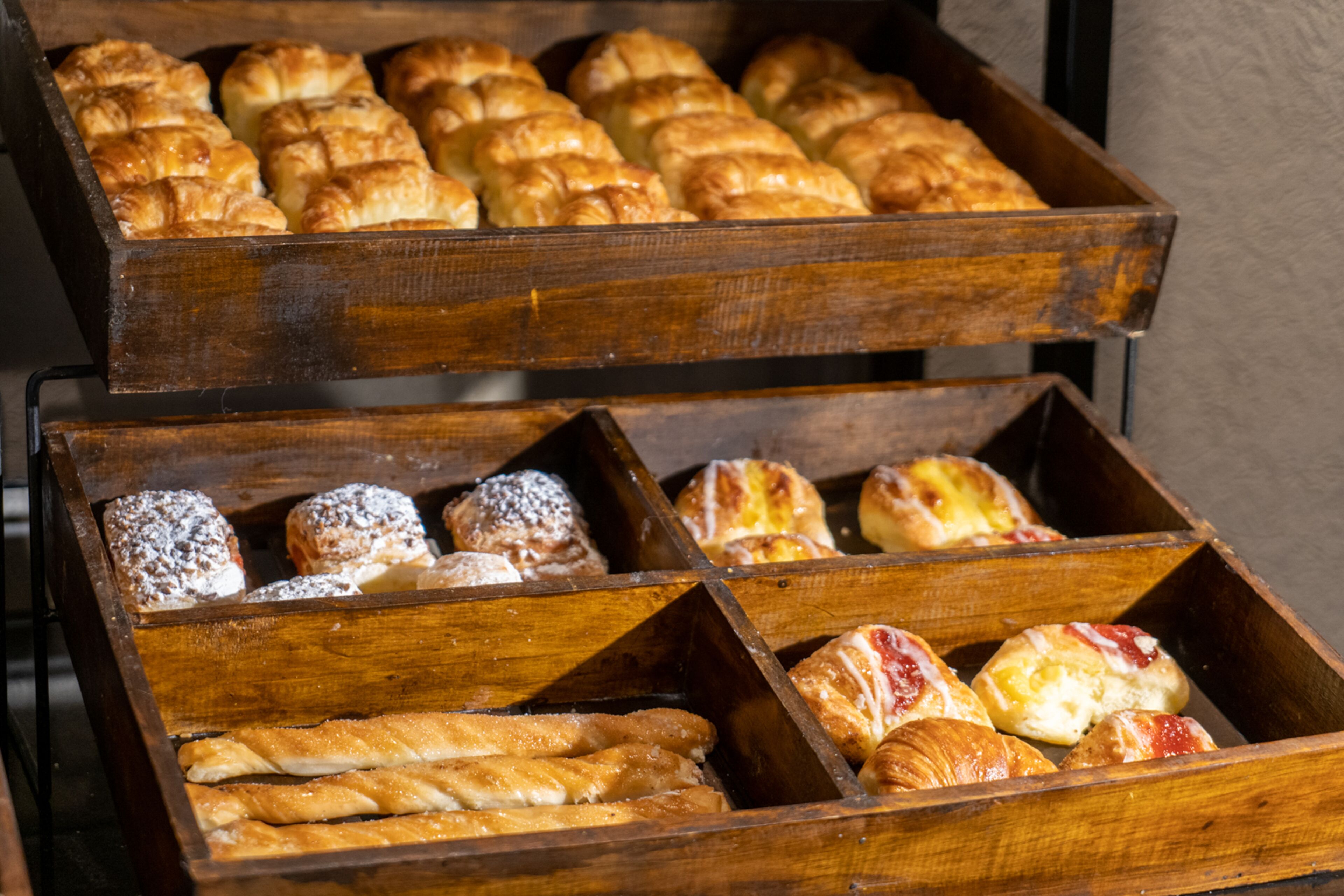 Una vitrina de madera con diversas opciones de repostería y panadería.