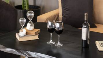 Un salón moderno con una mesa de centro de madera oscura, dos relojes de arena, dos copas de vino y una botella de vino.