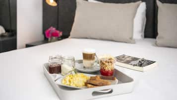 Bandeja de desayuno con huevos, tostadas, café y un libro sobre la cama.