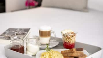 Bandeja de desayuno con tostadas, huevos revueltos, una taza de café y un vaso de leche sobre una cama en una habitación de hotel.