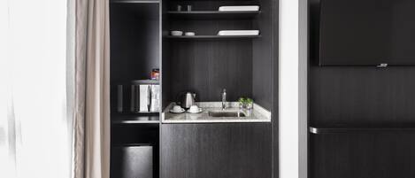 A compact kitchen with dark wood cabinetry, a built-in microwave, and a small sink area.