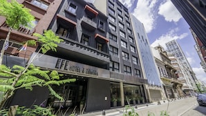 Un hotel moderno con un letrero que dice "HOTEL & COWORK", con un balcón, ventanas amplias y vista a la calle.