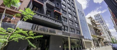Un hotel moderno con un letrero que dice "HOTEL & COWORK", con un balcón, ventanas amplias y vista a la calle.