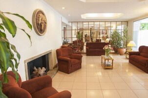 A spacious living room with a fireplace, several sofas, a coffee table, and a large window with a view.