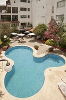 A swimming pool with a unique shape, surrounded by outdoor seating and potted plants.