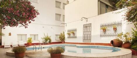 A courtyard with a swimming pool, potted plants, and outdoor seating.