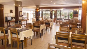 Un vaste espace dédié à la salle à manger, avec plusieurs tables et chaises, un coin café et de grandes fenêtres qui laissent entrer la lumière naturelle.