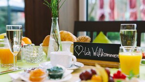 A breakfast setting with a variety of foods, drinks, and a sign that reads "Ich Wohlkommen". - ParkHotel Fulda (Fulda)
