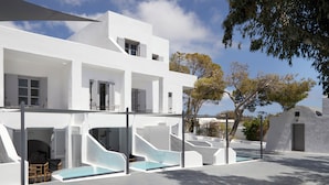 Un edificio moderno blanco con piscina, mobiliario exterior y un área cubierta.