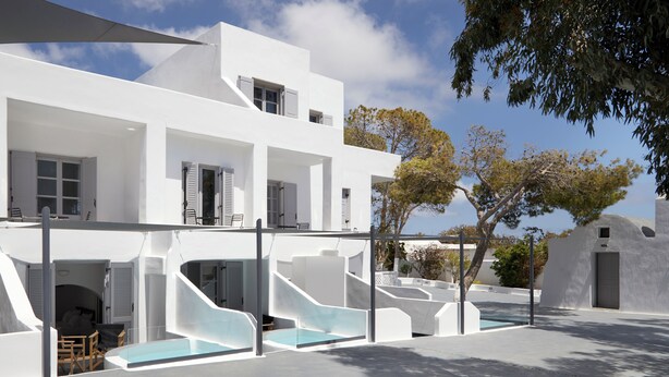 Un edificio moderno blanco con piscina, mobiliario exterior y un área cubierta.